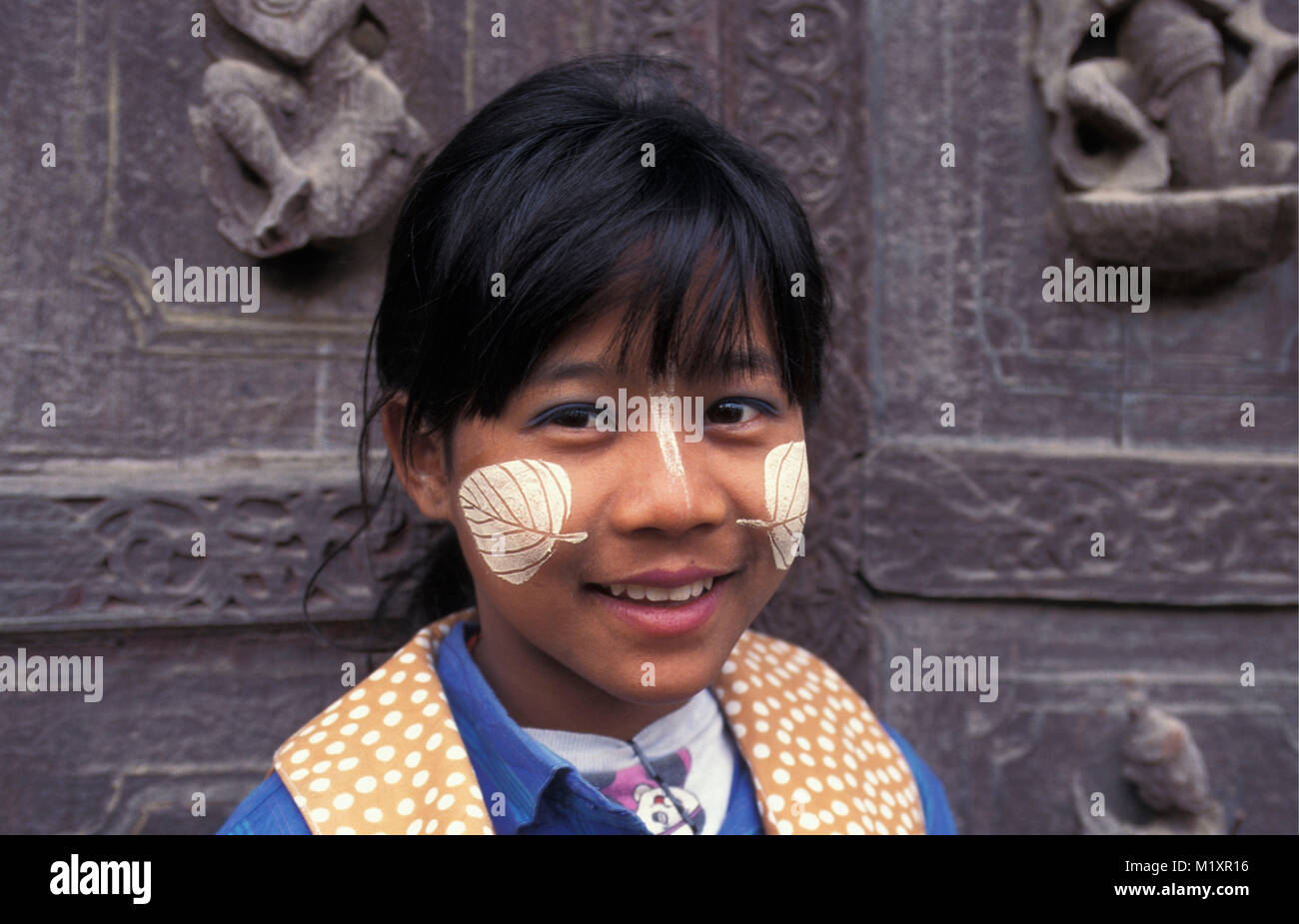Myanmar (Birmania). Mandalay. Chica con thanaka crema en forma de hoja (protección solar y decoración). Retrato. Foto de stock