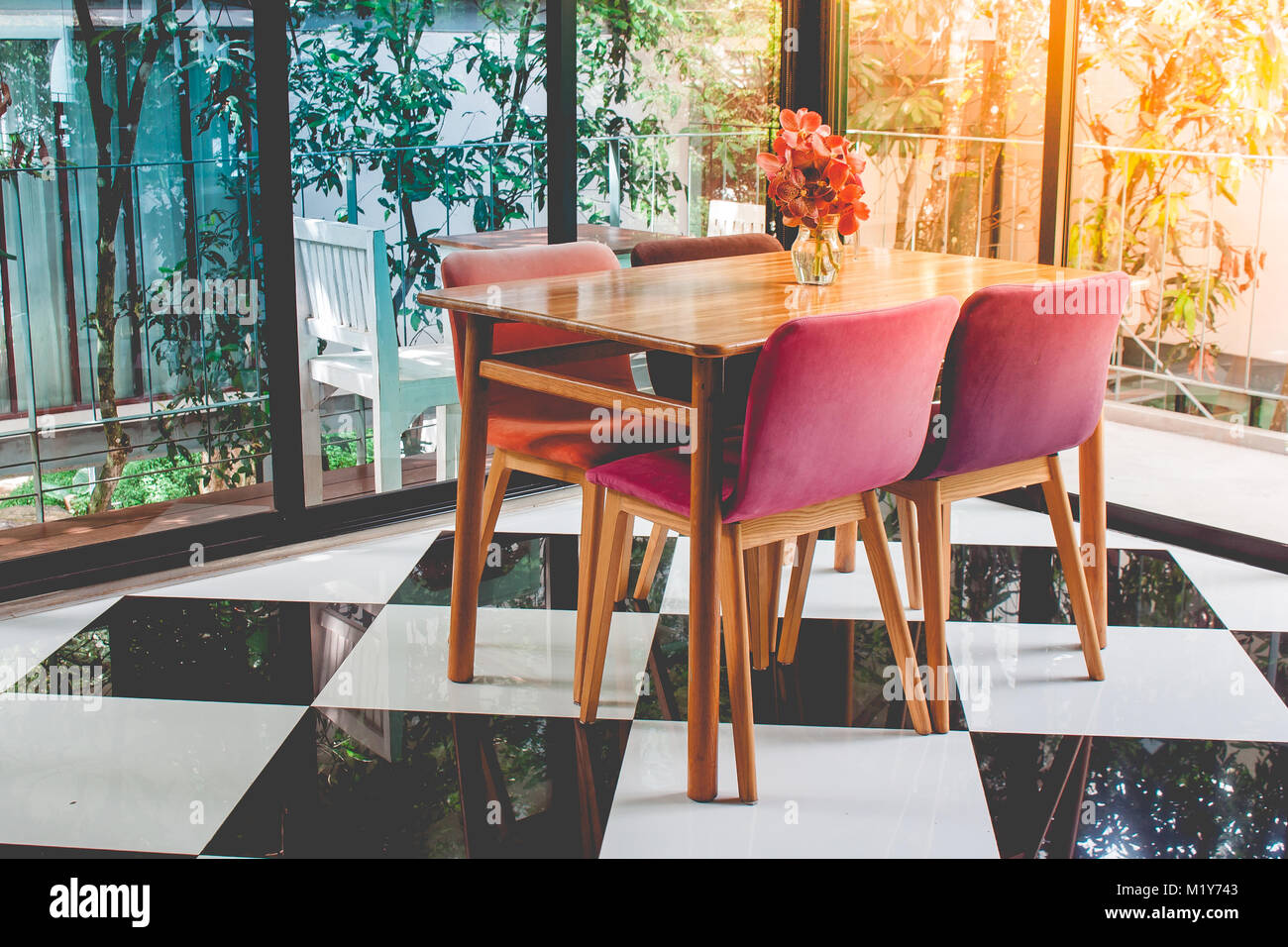 Vintage coloridas mesas y sillas de madera en damero piso en el restaurante con luz del sol irradian desde la esquina superior izquierda. Foto de stock