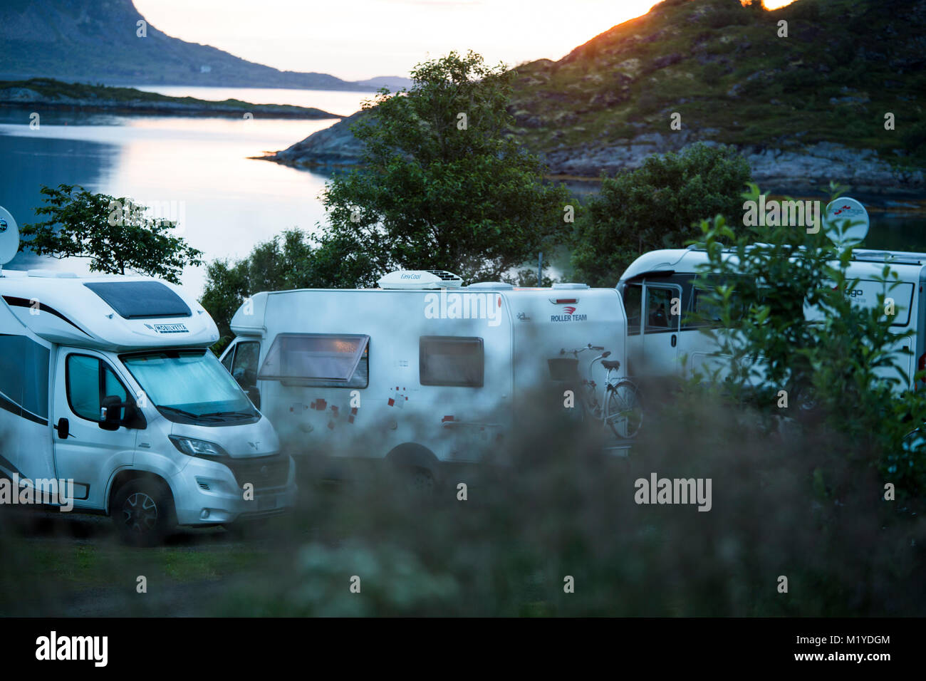 Tres RVs la noche aparcado cerca del mar o de un lago. Foto de stock