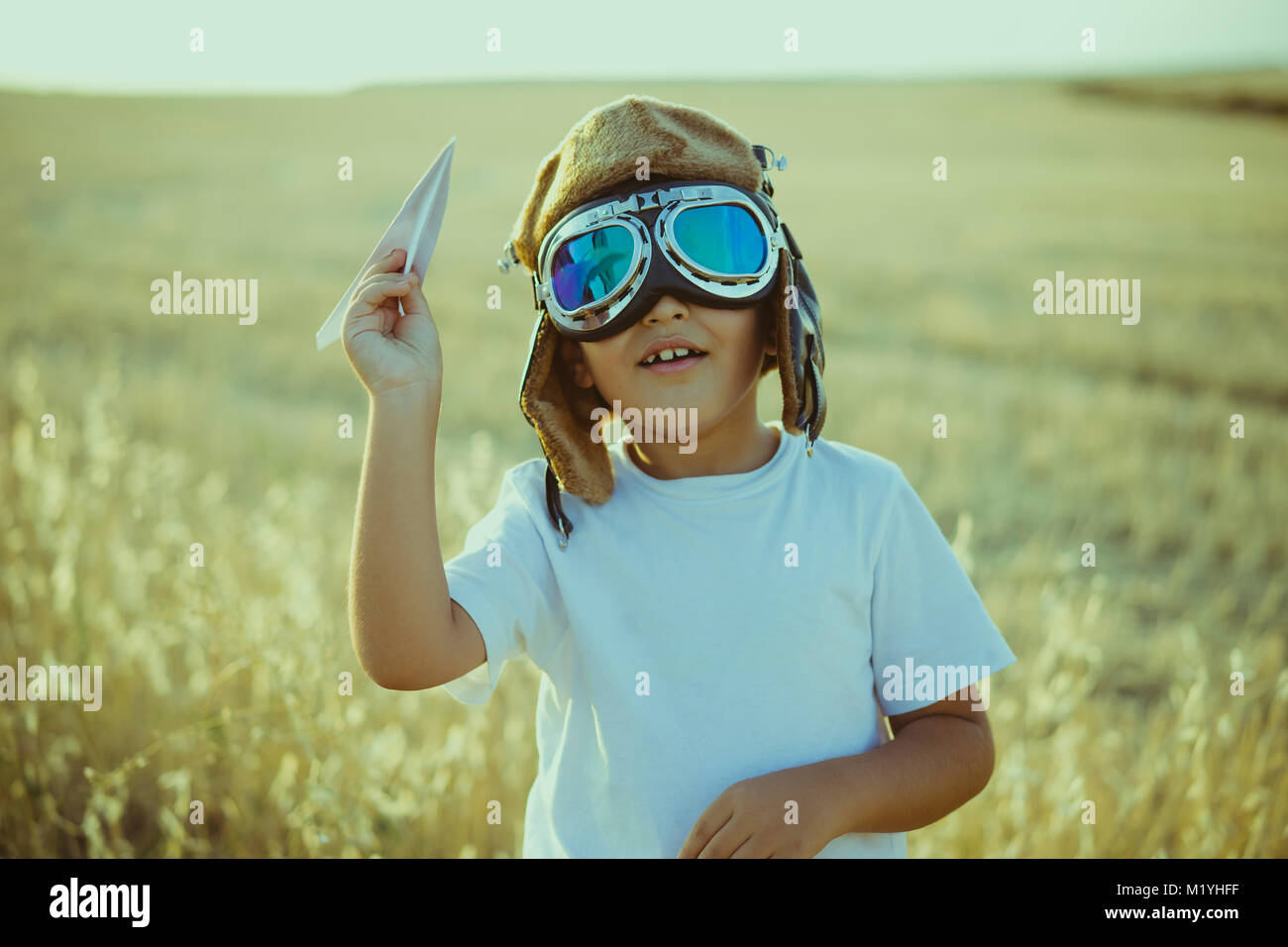 La imaginación, el niño que jugaba a ser piloto de avión, tipo gracioso con  gorra y gafas de aviador, lleva en su mano un avión de papel Fotografía de  stock - Alamy