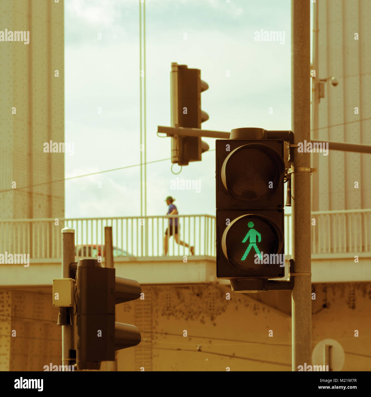 Persona solitaria corriendo entre construcciones de hierro y semáforos Foto de stock