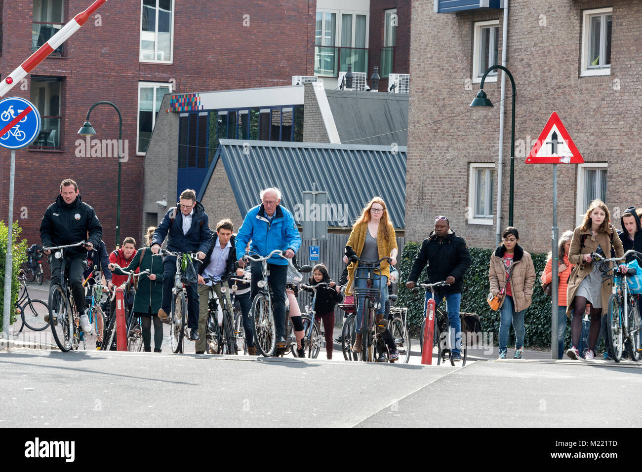 Ciclista esperando para cruzar la barrera se levanta al Oostpoortbrug, Ophaalbrug/ Puente levadizo de Delft Delft, Holanda. Foto de stock