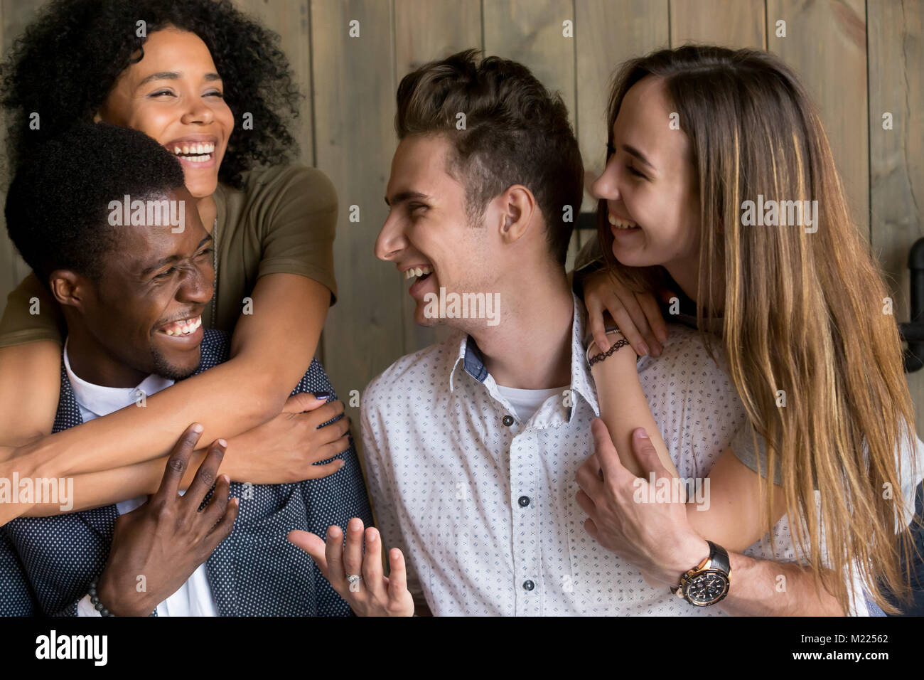 Dos parejas caucásicos y africanos feliz abrazando a divertirse tog Foto de stock