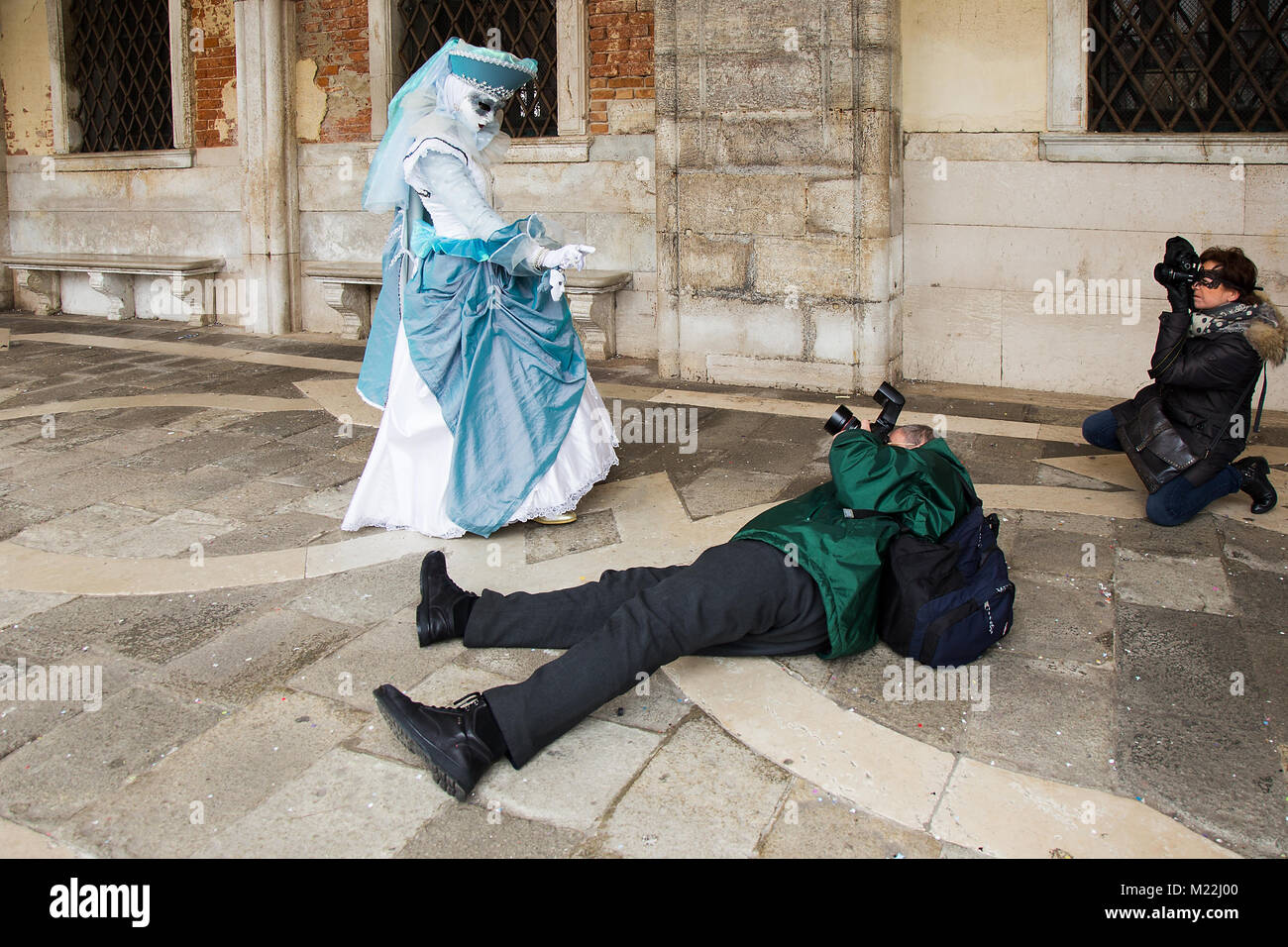 Carnaval de Venecia - el fotógrafo toma fotografías de máscara veneciana tumbado en el suelo con cámara DSLR, la Plaza de San Marcos en Venecia. Foto de stock