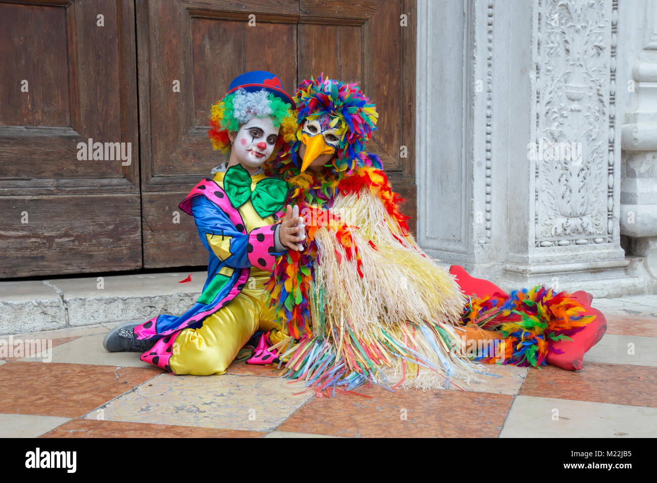 Máscara de bufón en Carnaval de Venecia - máscara de payaso en un colorido traje en la Plaza de San Marcos en Venecia. Foto de stock
