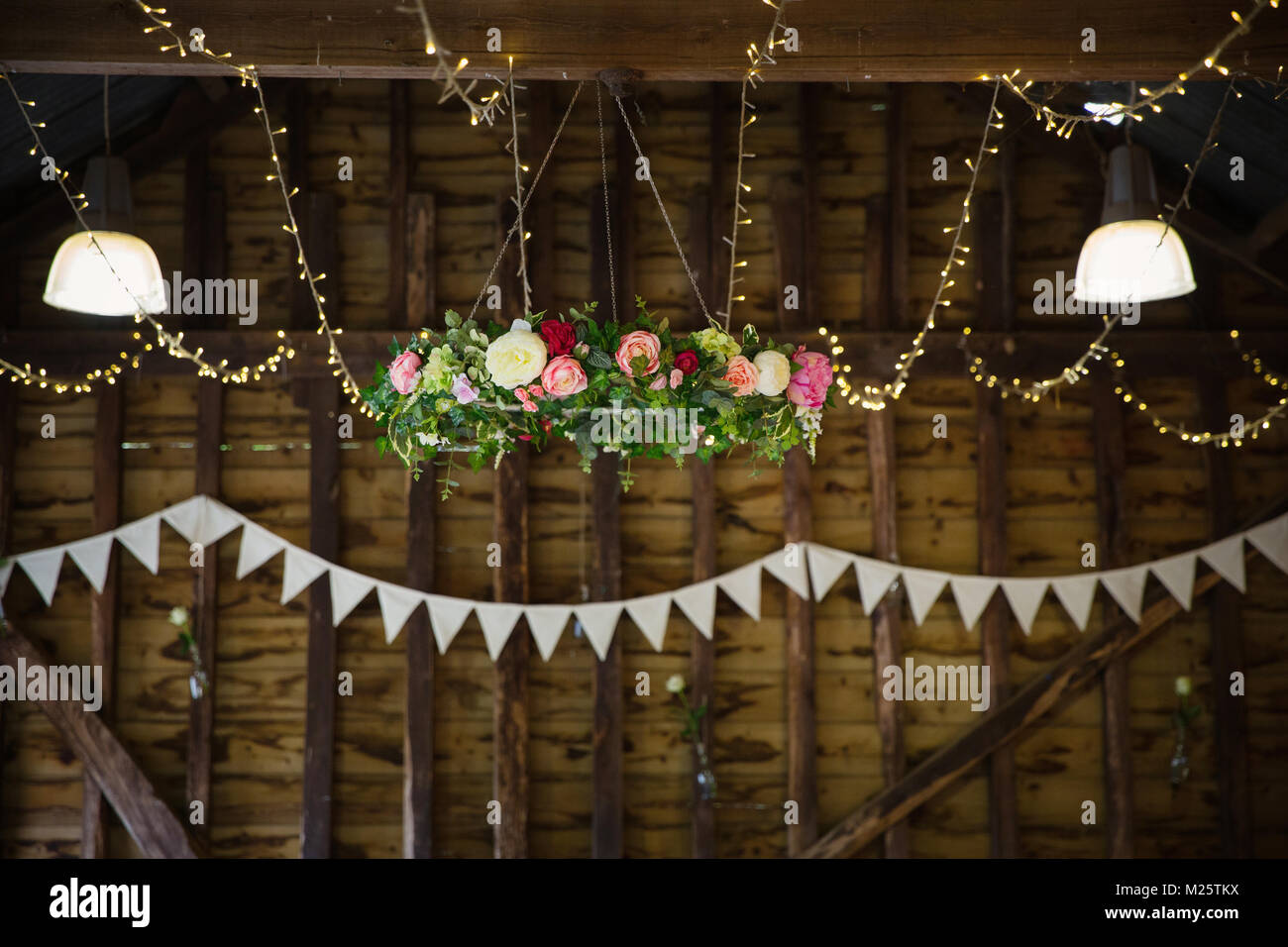 Barn interior con luces de cadena, arreglos florales y bunting Foto de stock