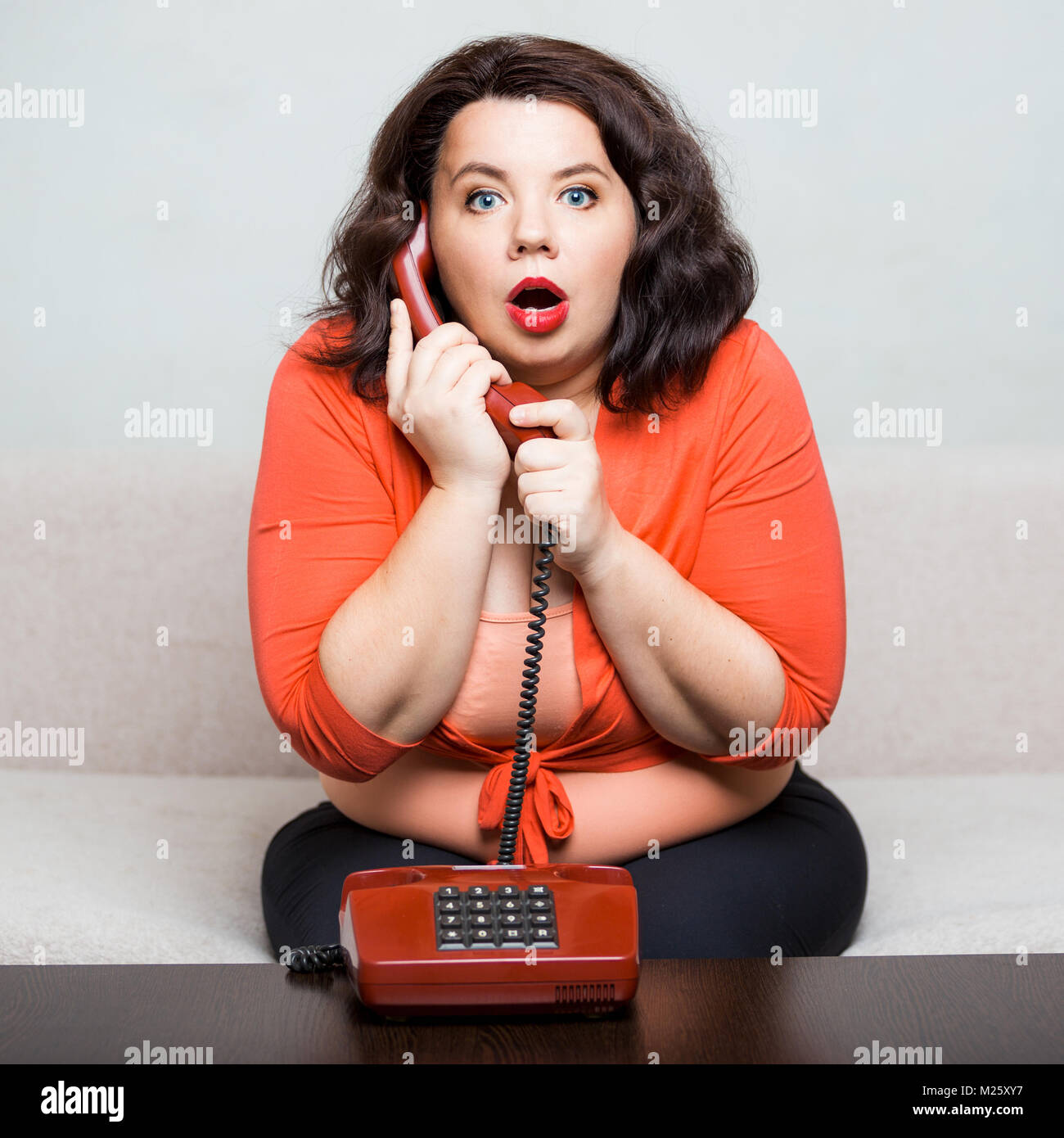 Retrato de una mujer adulta grasa sorprendió con un teléfono Foto de stock