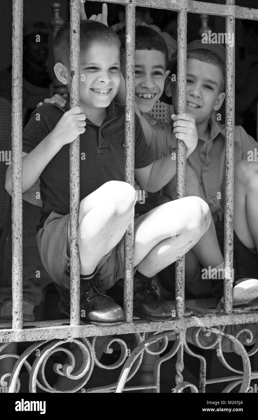 La vida cotidiana en Cuba - tres jóvenes mirando tras las rejas en La Habana, Cuba, Las Antillas, el Caribe, América Central - blanco y negro monocromo Foto de stock