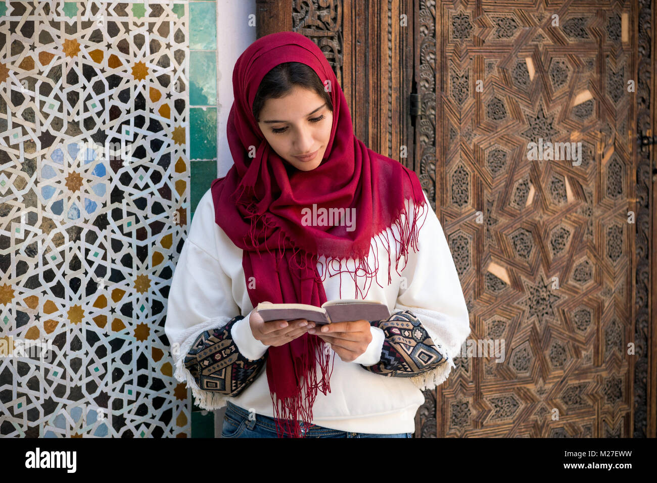 Prohibición Aplicando regla Mujer Árabe en vestimentas tradicionales con pañuelo rojo en la cabeza  leyendo un libro Fotografía de stock - Alamy