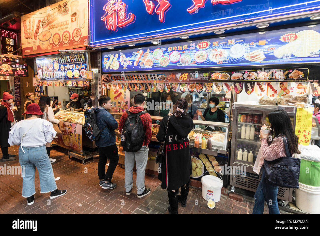 Hong Kong - 25 de enero de 2018: la gente compra diversos aperitivos, comida de la calle como el pescado y la carne bolas de pinchos, en un establo en las atestadas calles de Mong Foto de stock