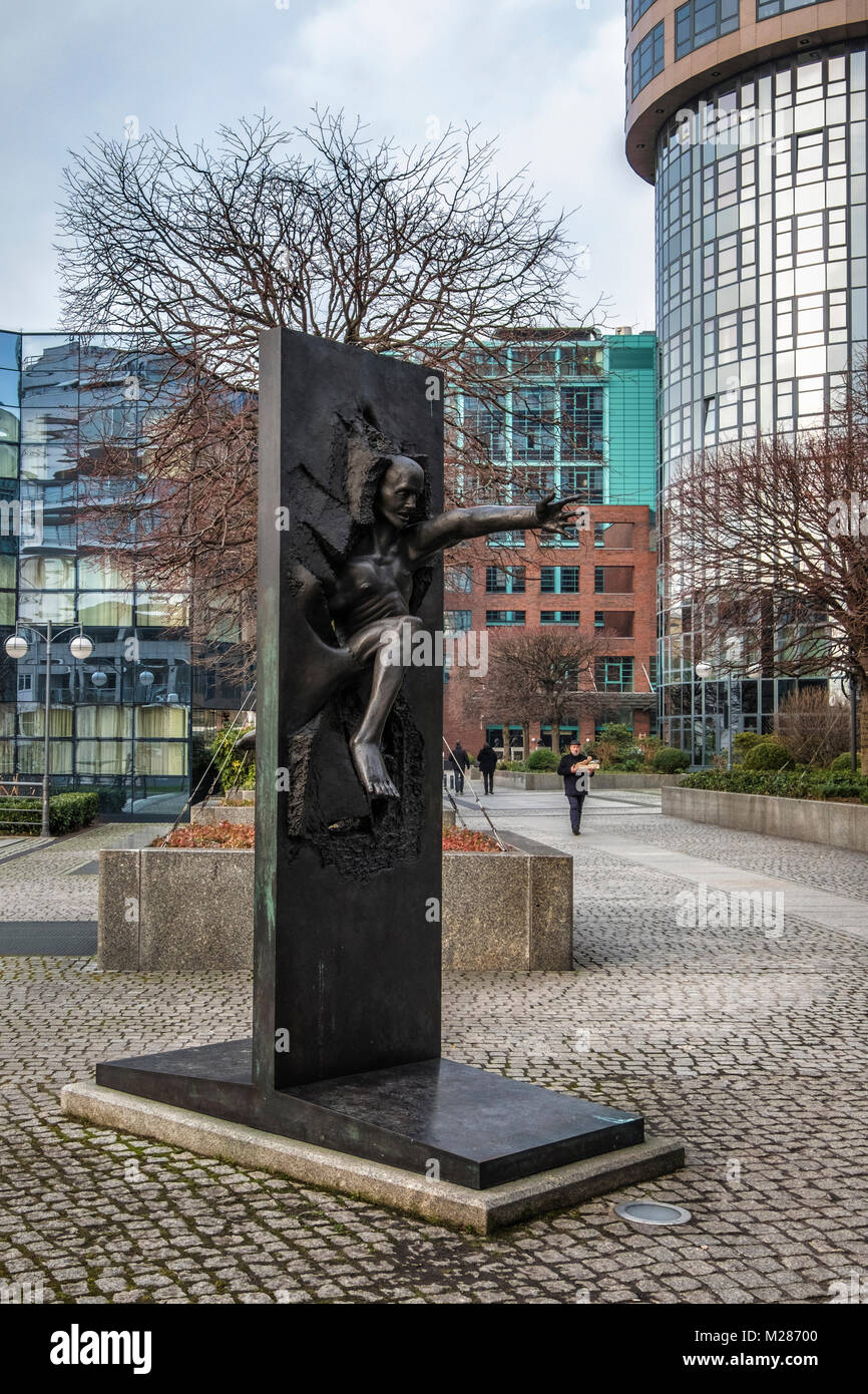 ,Berlín Mitte,Moabit. Escultura en bronce del hombre romper pared por Rolf Bibi - símbolo de la caída del Muro de Berlín, en la calle del recuerdo. Foto de stock