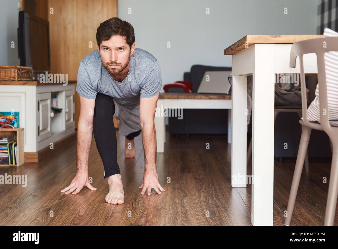 Colocar joven sportswear practicando yoga posturas en el suelo de su apartamento durante una sesión de ejercicio físico Foto de stock