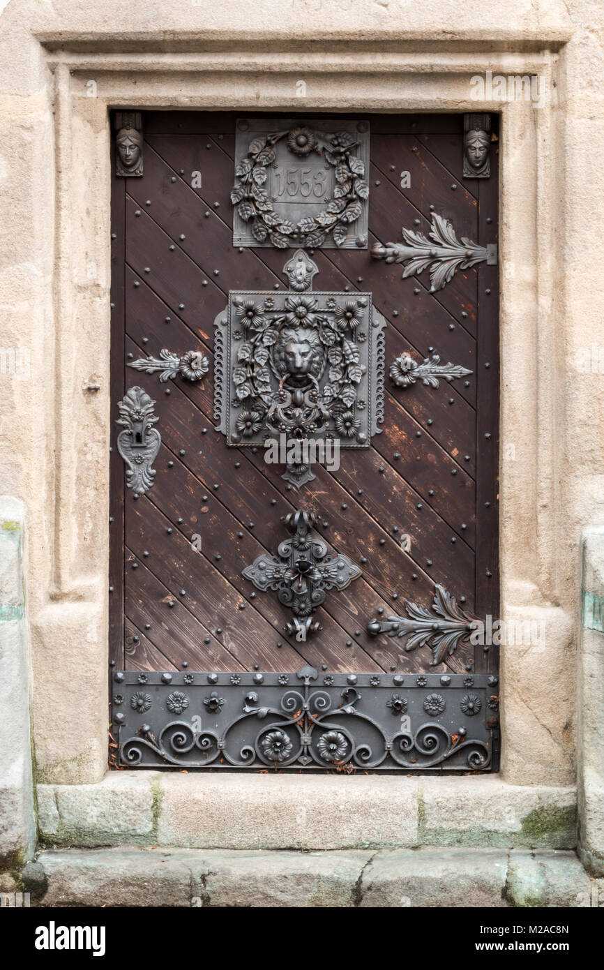 Detalle de una imagen de una puerta del siglo XVI de la antigua torre medieval con el bonito martinete león de hierro. Foto de stock