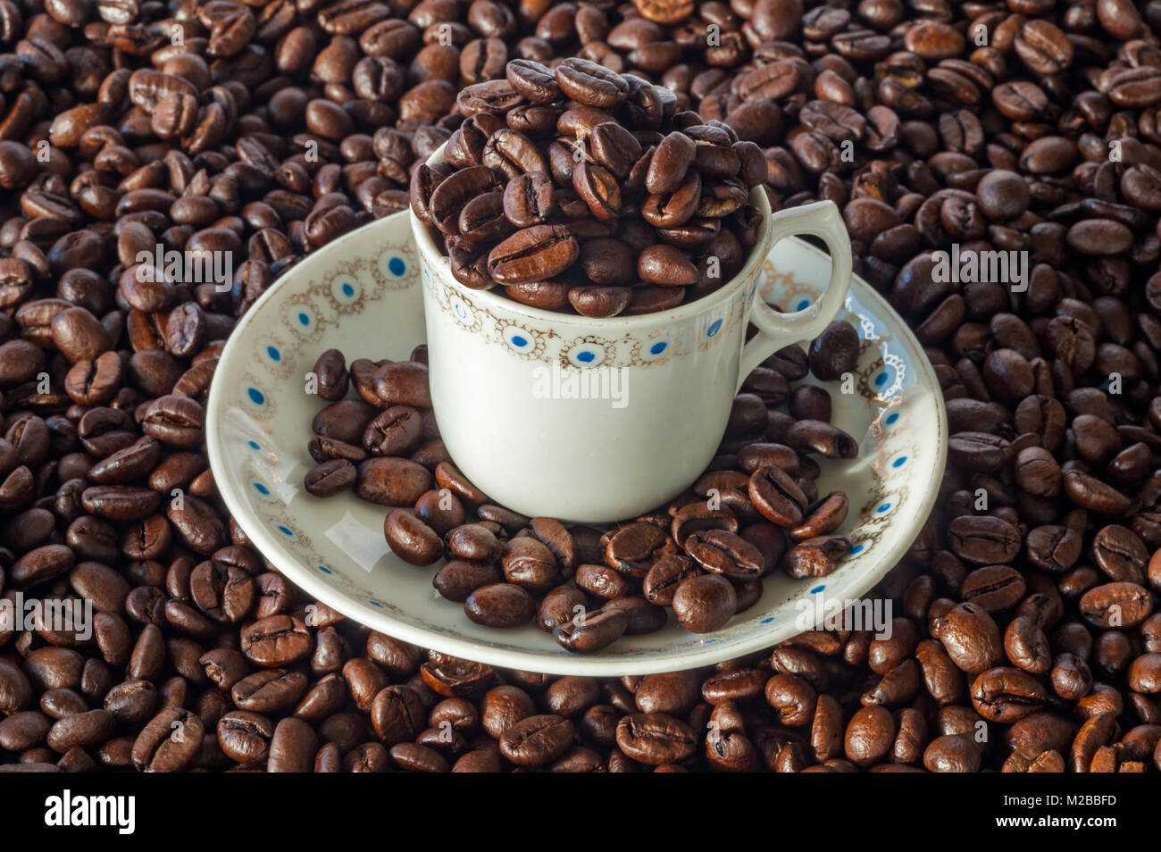 Taza y plato lleno de granos de café en un café espresso antecedentes concepto con espacio de copia. Foto de stock