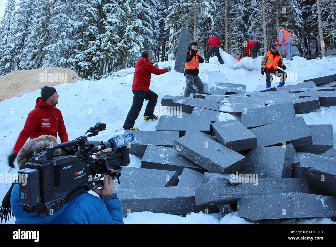 Öffnung des Schwarzwaldgletschers vor laufenden TV-Kameras - Vor zahlreichen Schaulustigen wurde am Samstag (30.11.2013) an der Hochfirstschanze Schmiedsbachtal im der Schwarzwaldgletscher von Titisee-Neustadt geöffnet. Mit dem Schnee vom vergangenen Invierno, unter der Styroporplatten, Sägemehl und Plastikfolien übersommert hat, wird jetzt die Hochfirstschanze mit Schnee belegt. Dort werden vom 13. bis 15. Dezember 2013 wieder zwei FIS Weltcup-Skispringen ausgetragen. Medidor zehn der hohe und 65 metros lange Schneeberg umfasst etwa 7.000 Kubikmeter. Foto de stock