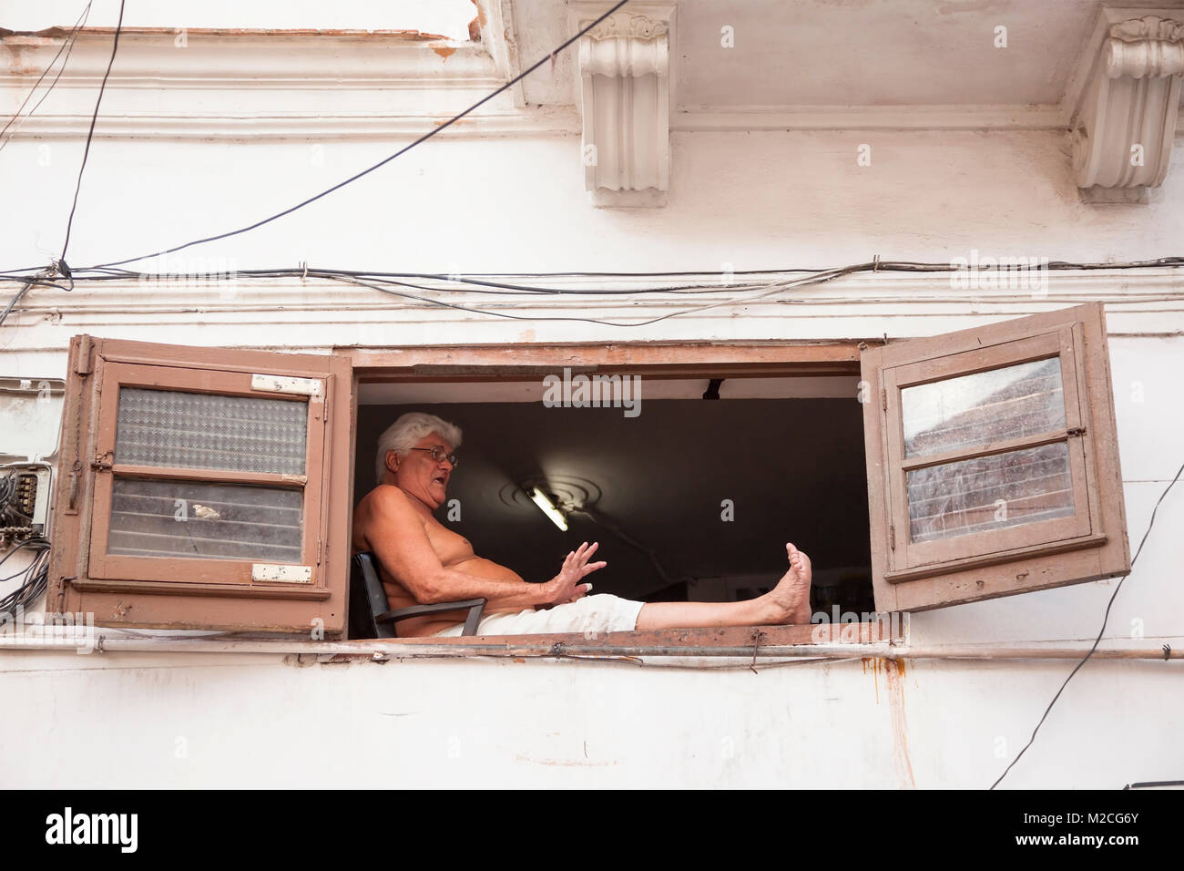 Un hombre cubano sentado en un alféizar en La Habana, Cuba. Foto de stock