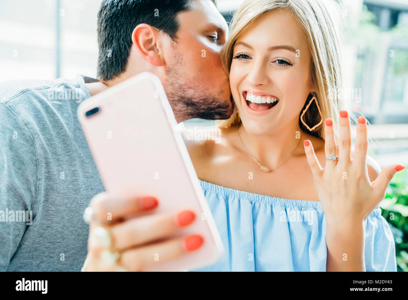 Pareja caucásica tomados de la mano y posar para selfie con anillo de compromiso Foto de stock