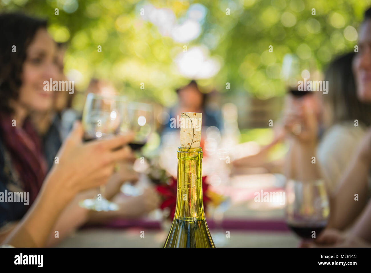 El corcho de una botella de vino cerca de gente bebiendo vino Foto de stock