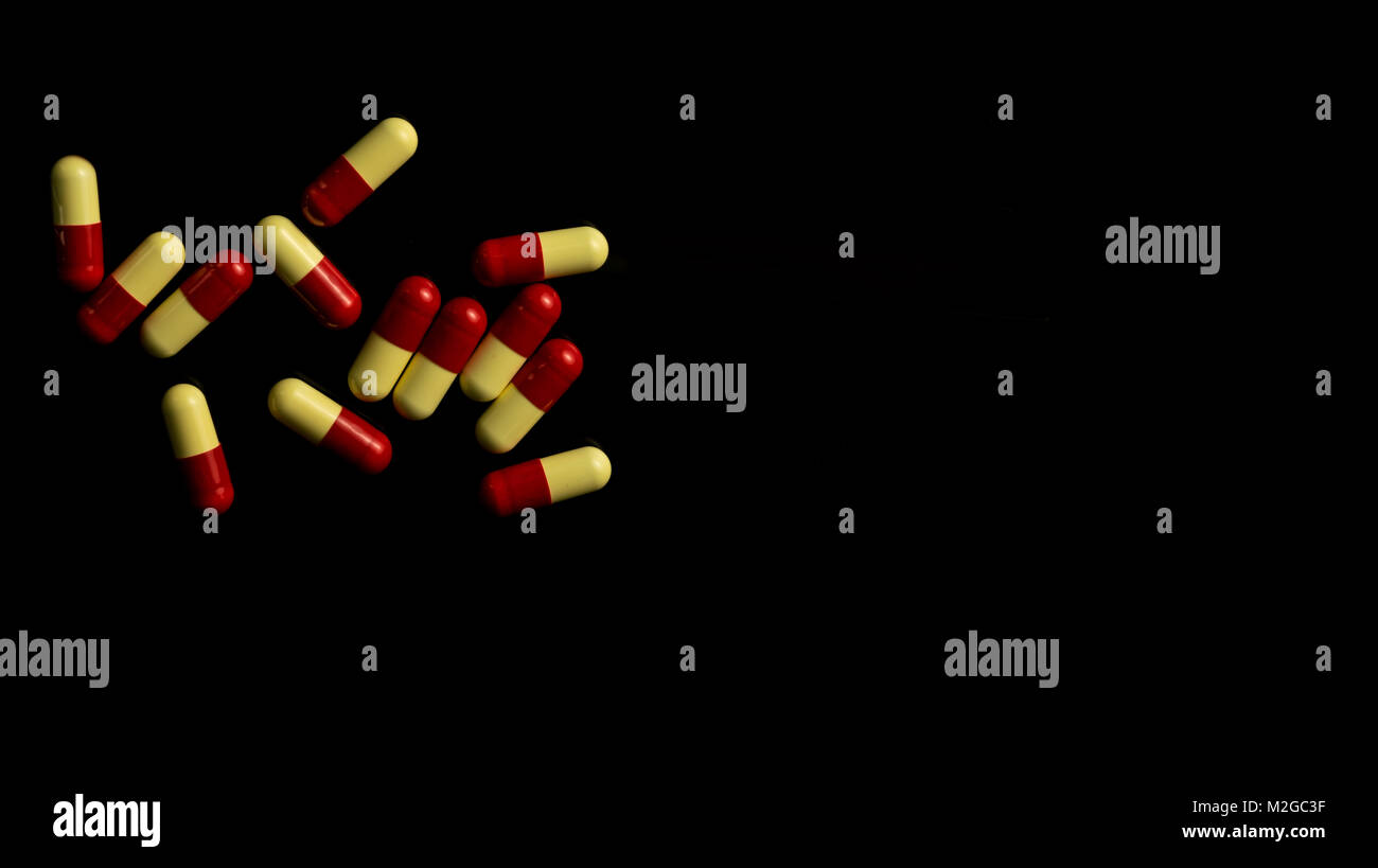 Rojo, amarillo capsule pills sobre fondo oscuro. Concepto de resistencia antimicrobiana. Foto de stock
