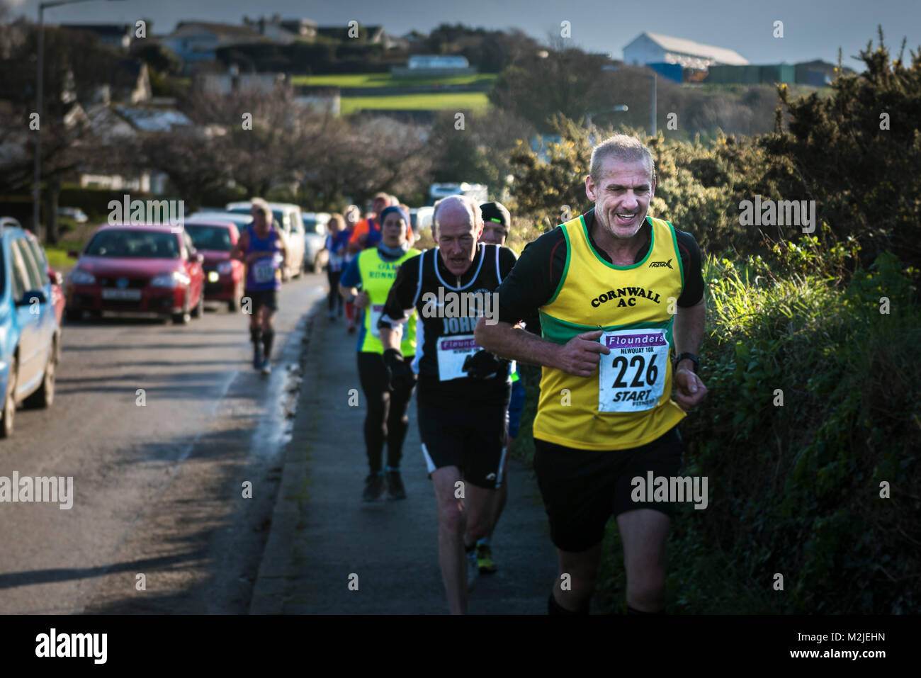 Mature corredores compitiendo en una carrera de carretera en Newquay, Cornwall. Foto de stock