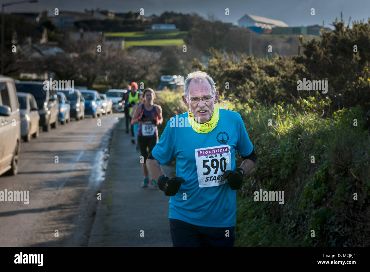 Un maduro corredor compitiendo en una carrera de carretera en Newquay, Cornwall. Foto de stock