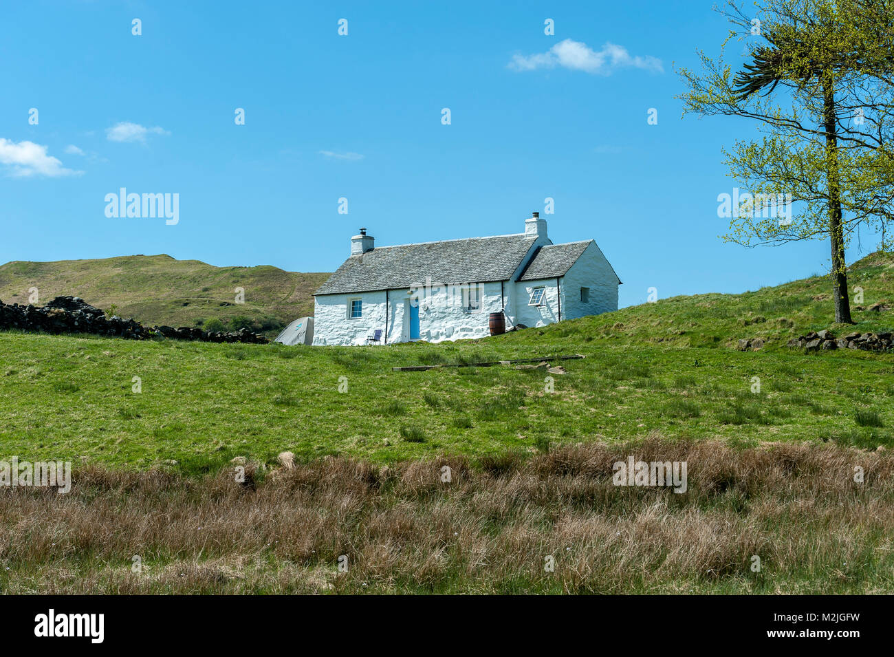 Scottish Highland casa rural enclavada en el cielo azul alrededor de la isla de Seil Foto de stock