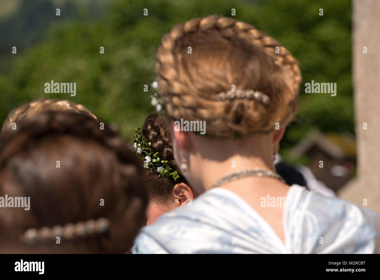 Las mujeres jóvenes vistiendo trajes nacionales y peinados trenzados, vista  posterior, detalle Fotografía de stock - Alamy