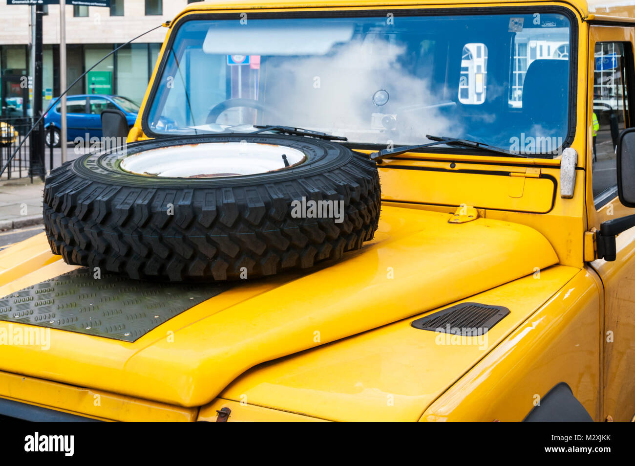 Rueda de repuesto montada sobre el capó de un Land Rover Defender amarillo vehículo 4x4. Foto de stock