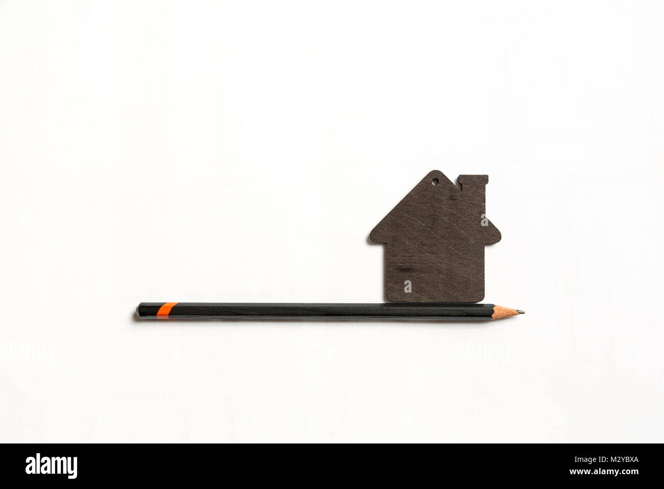 Imagen del modelo negro pequeño de una casa con lápiz negro sobre un fondo blanco. Foto de stock