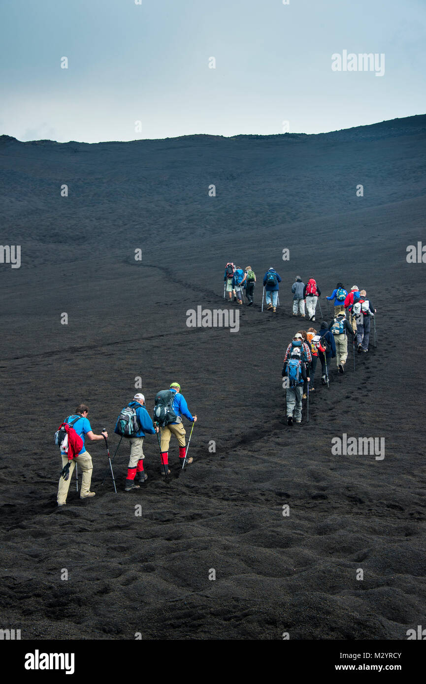 Los turistas que caminan en una línea a través de la arena de lava del volcán Tolbachik, Kamchatka, Rusia Foto de stock