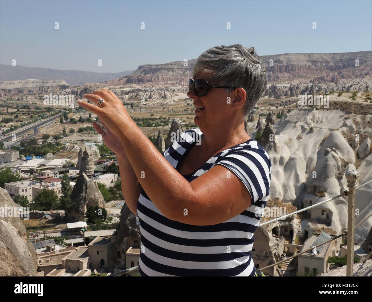 Una señora inglesa turista tomando fotos del impresionante goreme, Capadocia en Turquía Foto de stock