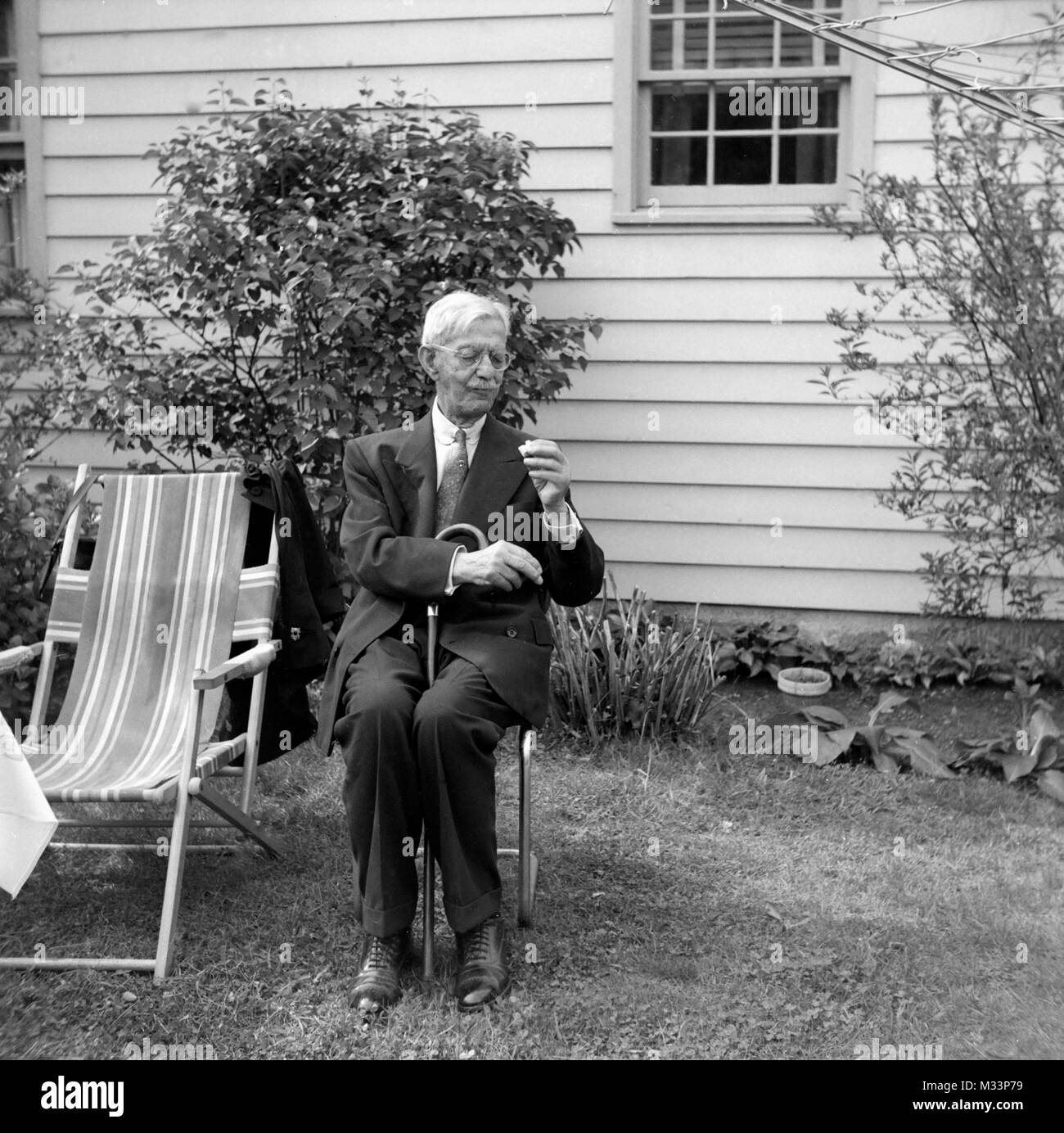 Hombre Senior examina un bocado de comida antes de comerla, ca. 1946. Foto de stock