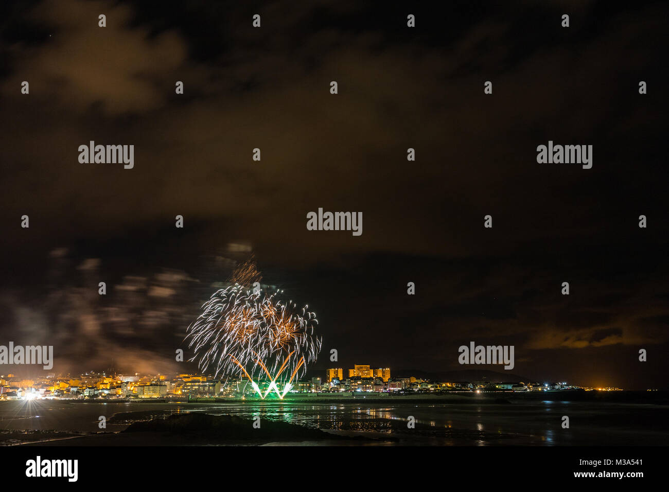 Vacaciones en la costa gallega, donde por la noche celebrando las festividades en la ciudad de Foz, España, contemplamos los fuegos artificiales dignos de admiración Foto de stock