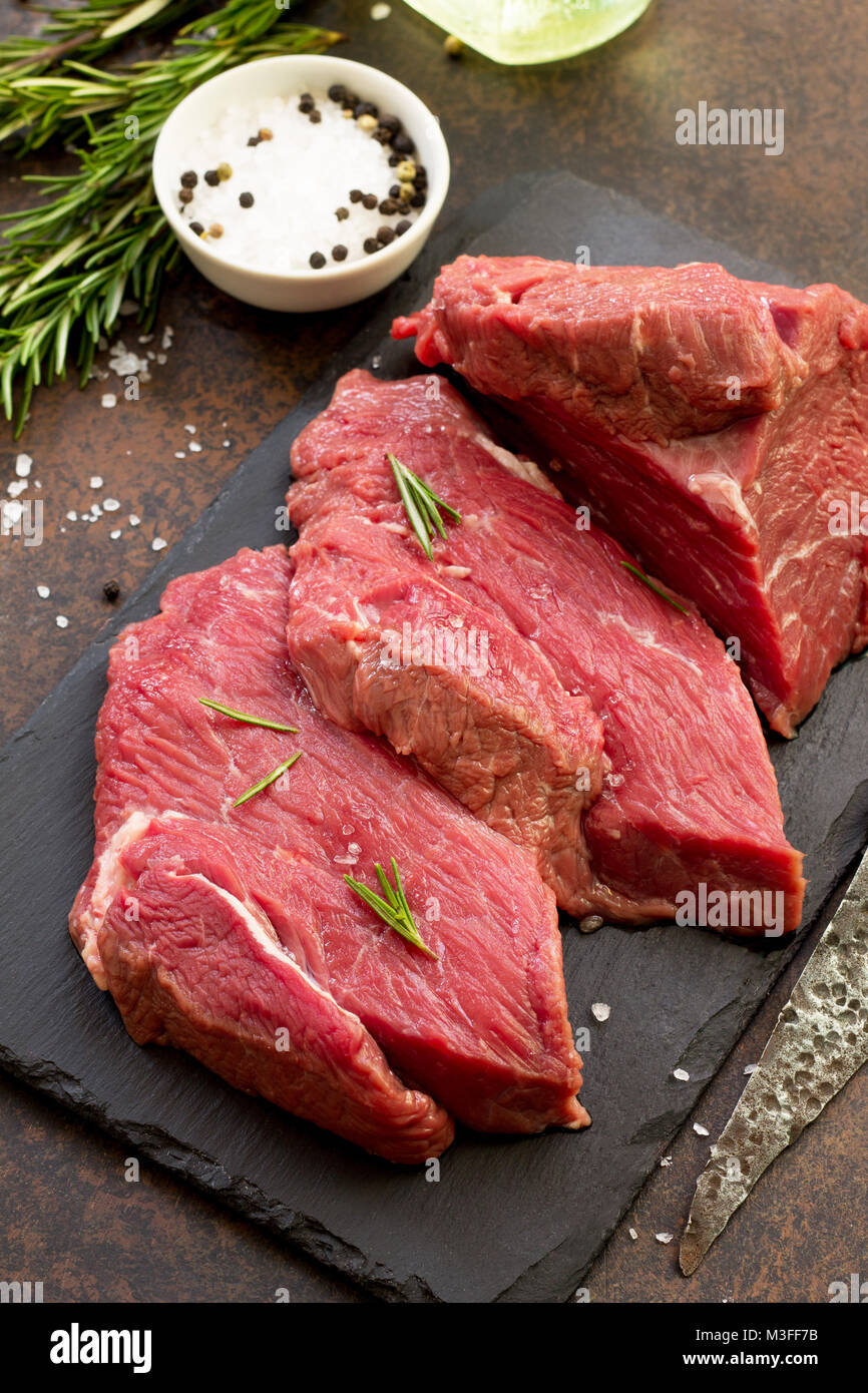 La carne fresca. Cheese steak carne sobre una tabla para cortar, pizarra,  especias y limón romero fresco sobre una mesa de piedra Fotografía de stock  - Alamy