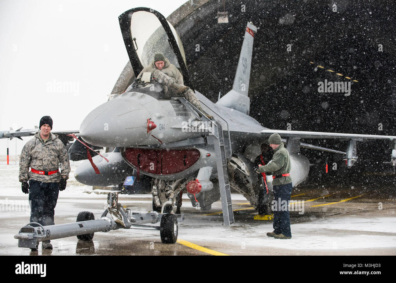 Un equipo de mantenimiento prepara un F-16cm combates aviones Falcon para ser empujado en una aeronave endurecido refugio en la Base Aérea de Spangdahlem, Alemania, el 6 de febrero de 2018. Una tormenta de nieve poner fin a las operaciones de vuelo para el día, pero no detuvo la necesidad para el mantenimiento general de Spangdahlem la flota de F-16s. Los aviadores asignados a la 52ª AMXS están encargados con el cuidado y mantenimiento de los aviones de Estados Unidos, especializada a la supresión de las defensas aéreas del enemigo (SEAD) papel en el teatro europeo de operaciones. (Ee.Uu. Fuerza Aérea Foto de stock