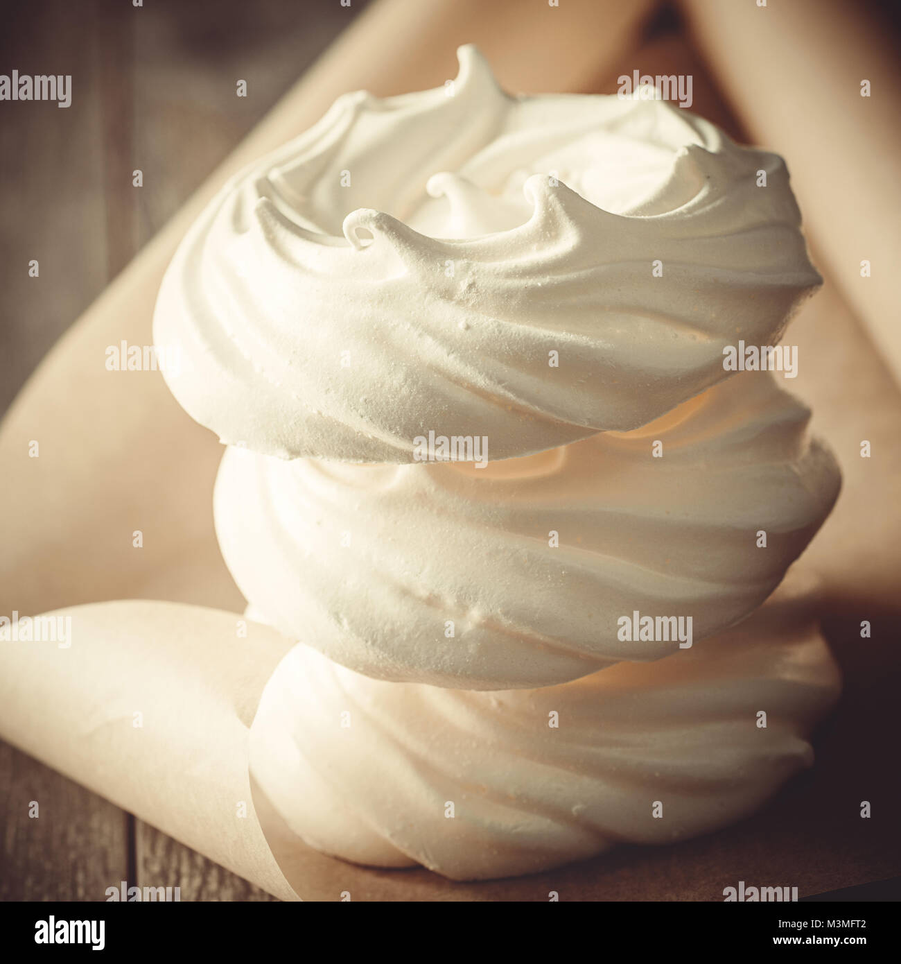 Cerca de una pila de tres nidos de merengue sobre papel pergamino - formato cuadrado ideal para instagram Foto de stock