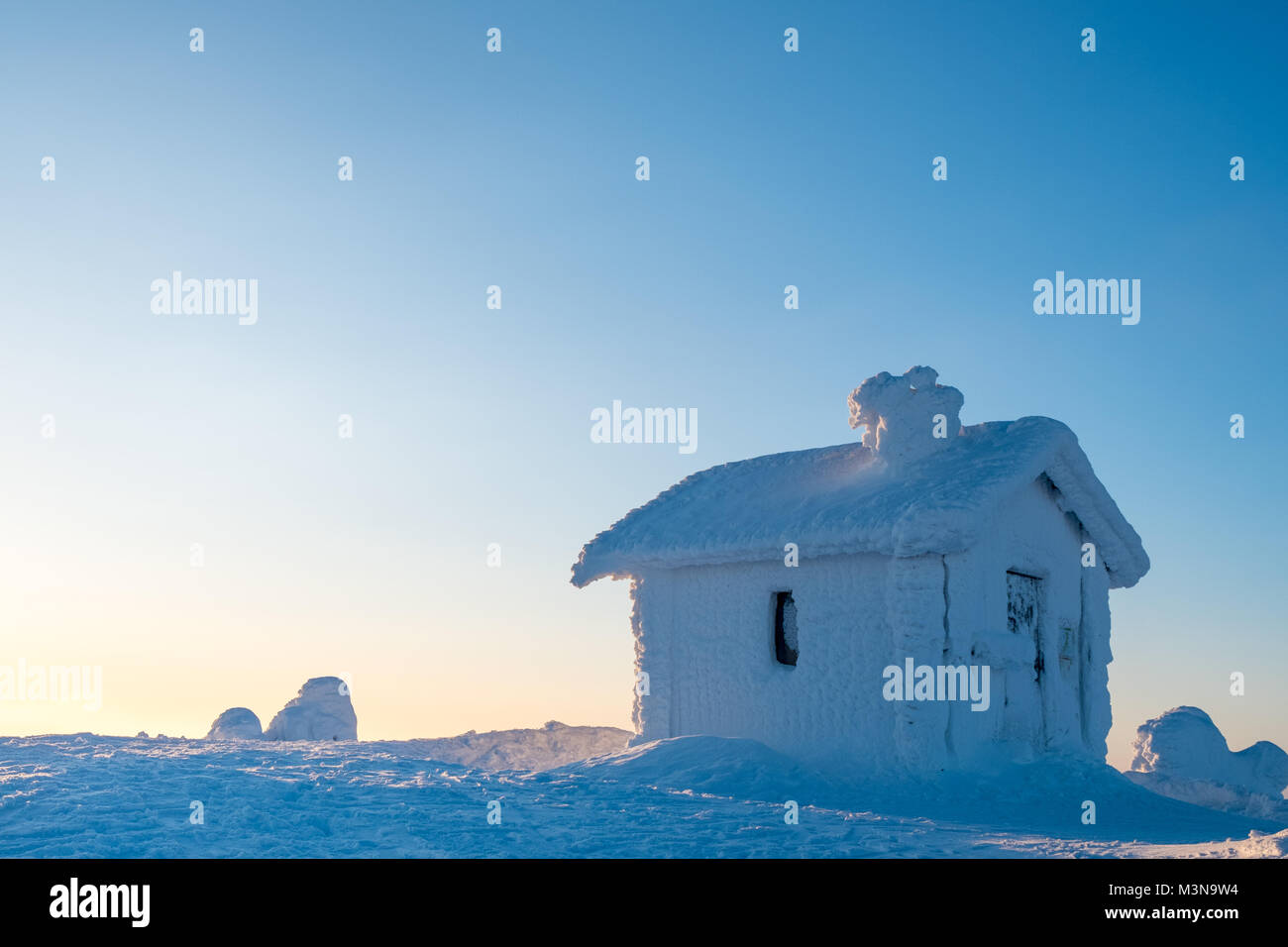 Cabina incrustada en la nieve en la cima de una colina en Finlandia Foto de stock