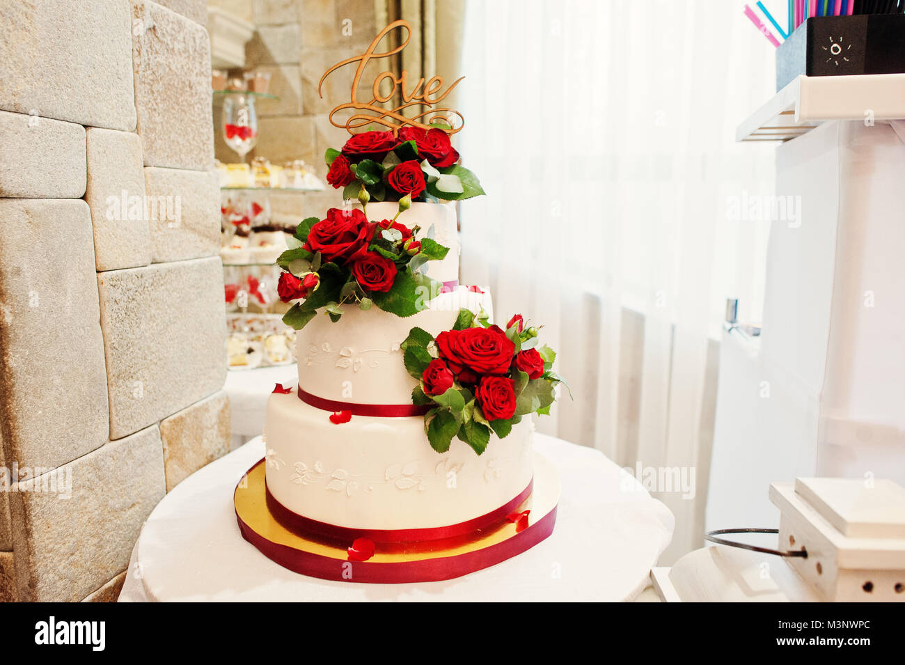 La foto de un gran pastel de bodas blanco y rojo decorado con rosas rojas  frescas Fotografía de stock - Alamy