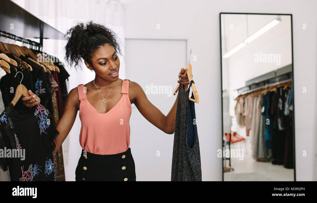 Diseñador de moda femenina mirando vestidos de diseñador en su estudio de moda. Cliente comparando los vestidos en una boutique de moda. Foto de stock