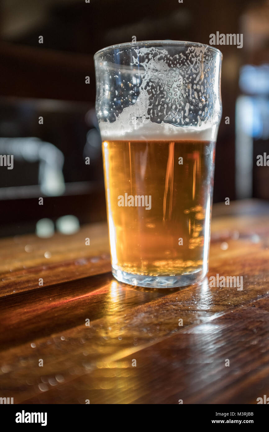 Lleno hasta la mitad con pinta de cerveza en el pub tabla Foto de stock