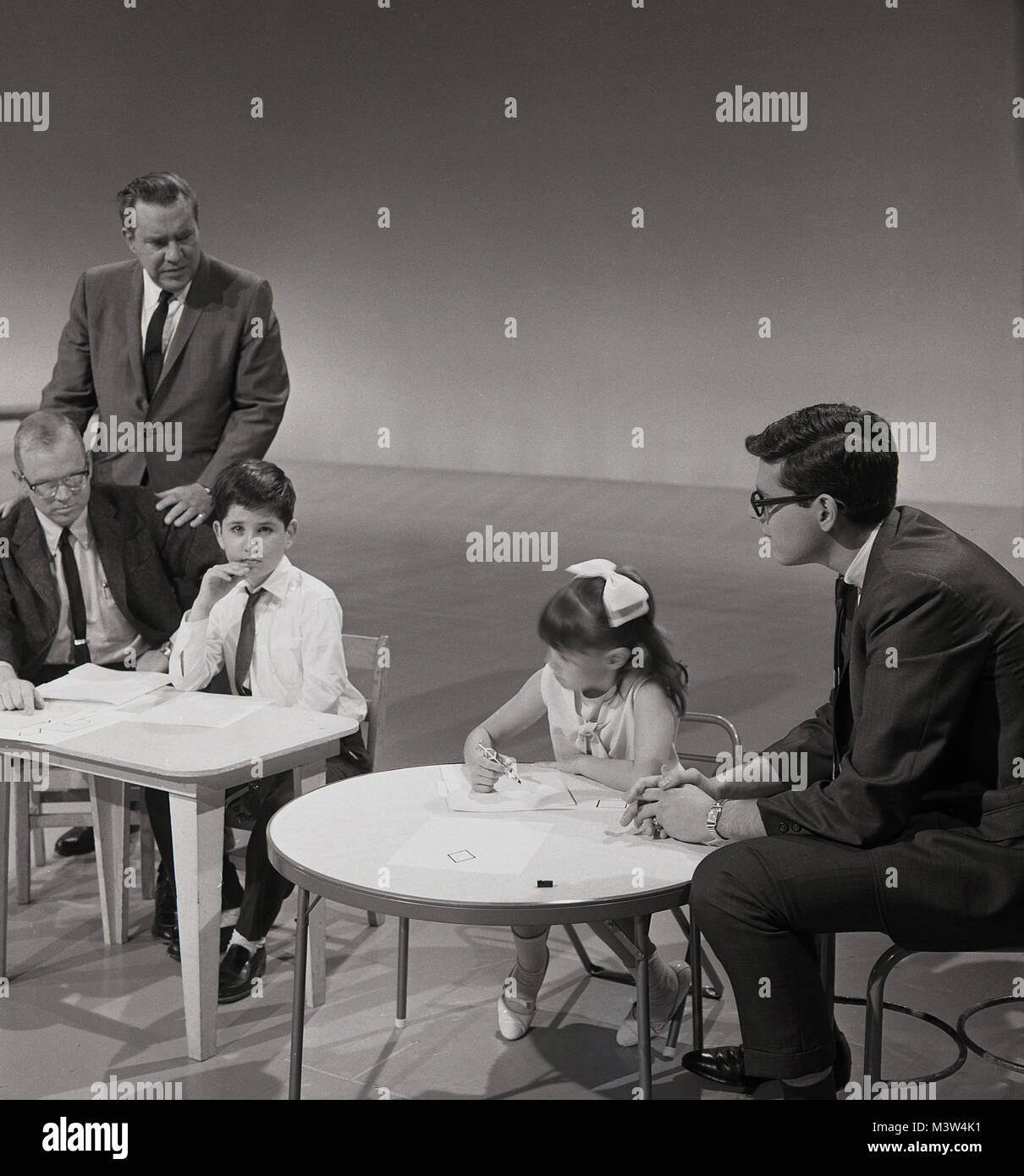1960, histórica, la imagen se muestra a una niña y un niño sentado en mesas pequeñas en un estudio de televisión tomando parte en el programa de televisión con niños más brillantes de América, EE.UU. competencia. Foto de stock