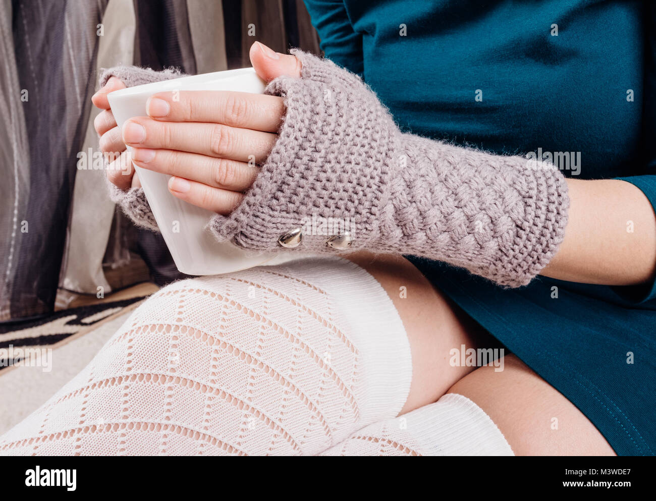Las manos de una niña en guantes dedos mantenga una taza de té blanco Fotografía stock - Alamy