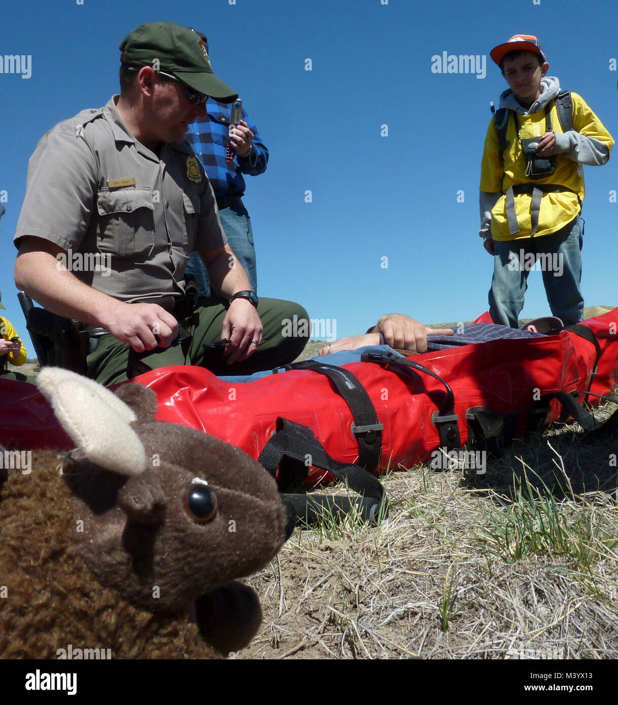 Los jóvenes estudiantes en Parque Nacional. Buddy Bison mira mientras Eric Yount Ranger demuestra el transporte Foto de stock