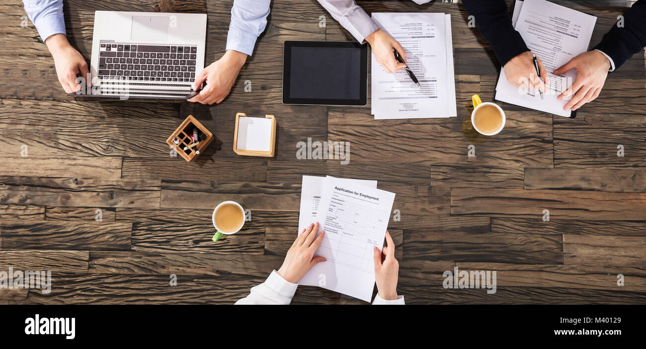 Vista elevada de empresarios teniendo una entrevista sobre el escritorio de madera en la oficina Foto de stock