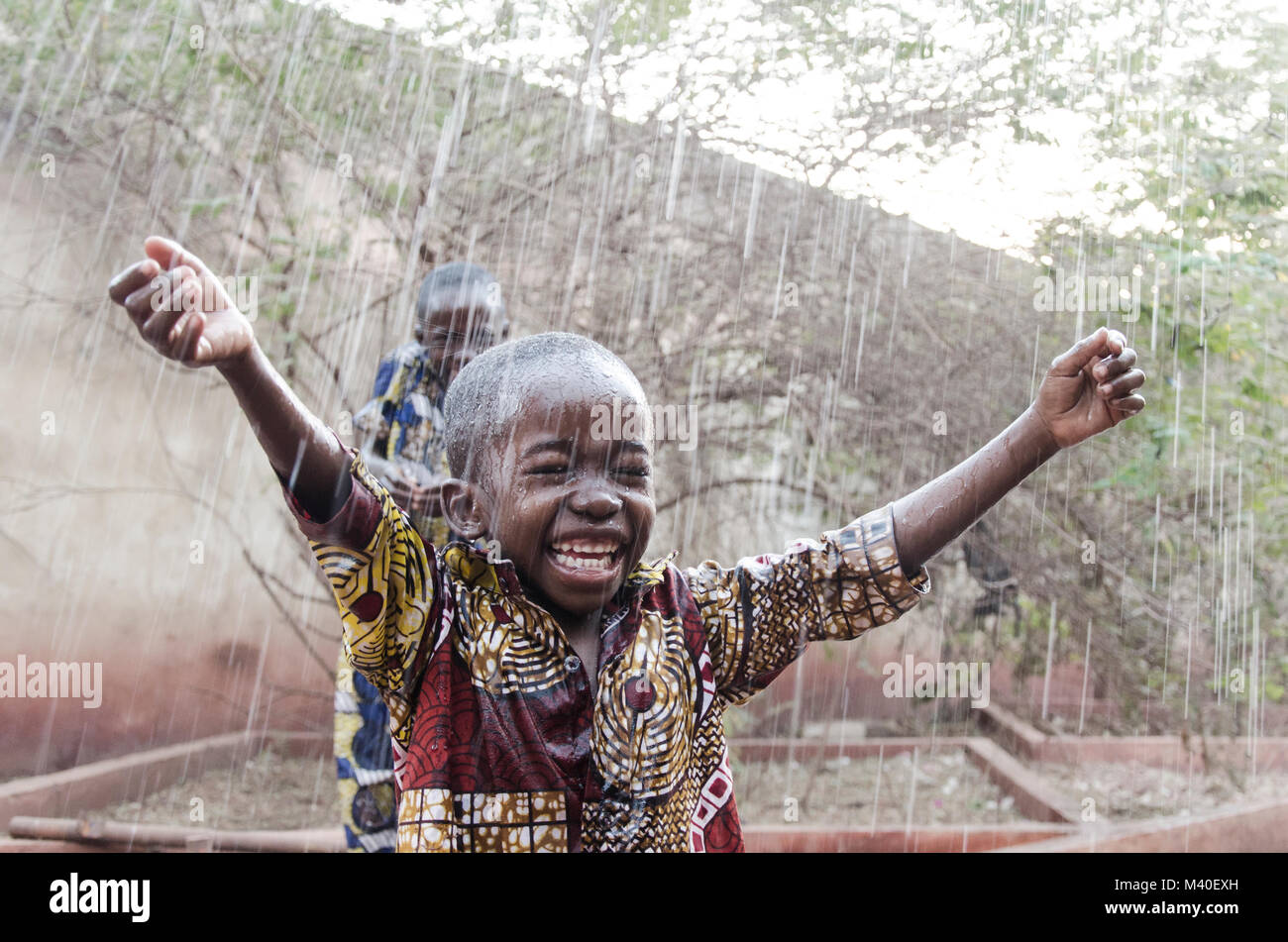 Par de negros africanos niños jugando bajo la lluvia. Símbolo de la hermandad, Agua para África. Editorial franco rodada en las calles de Bamako, Malí. Foto de stock