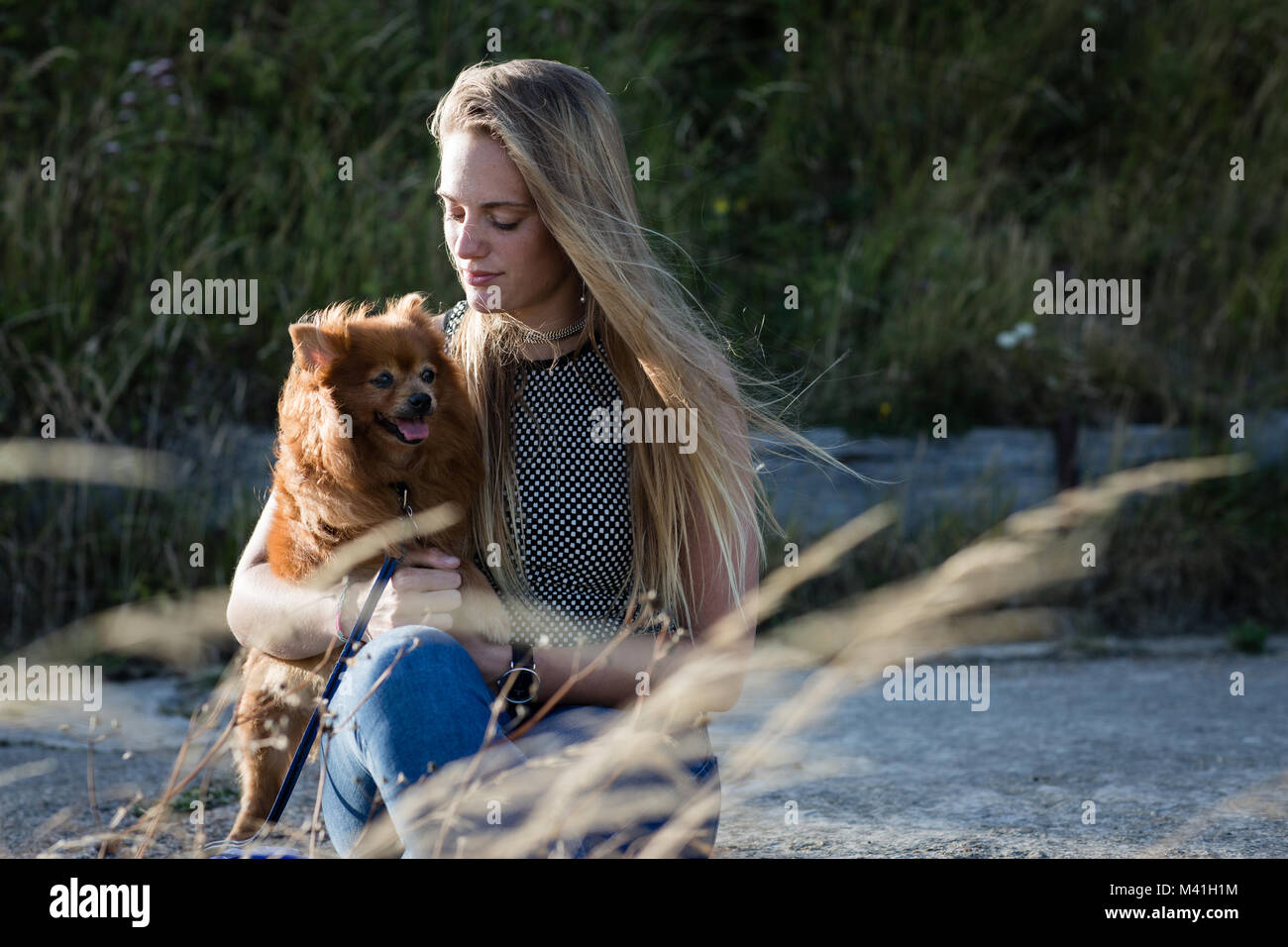 Las hembras jóvenes de mimar a su perro mascota en campo Foto de stock