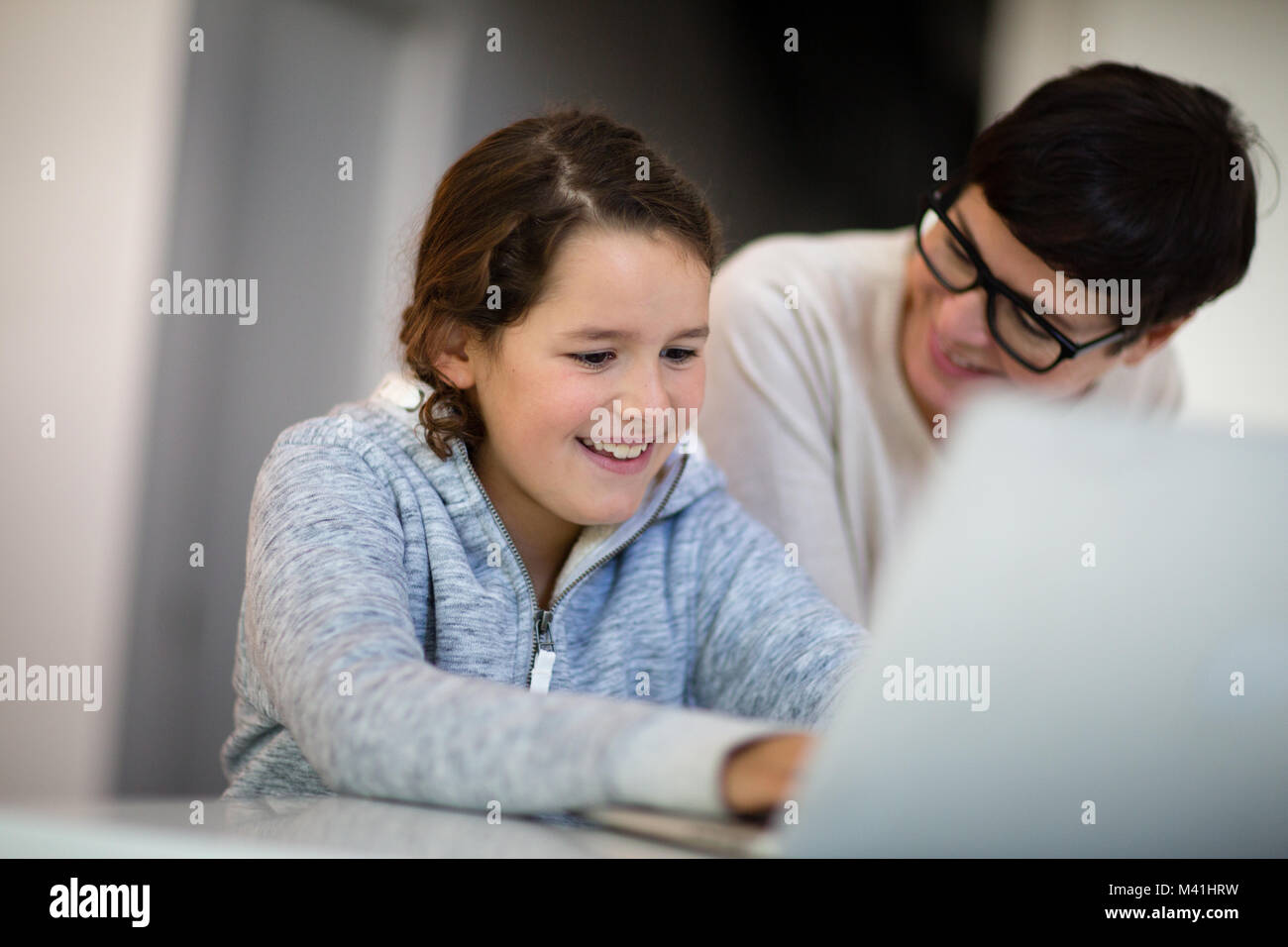 Hija haciendo los deberes en el portátil Foto de stock