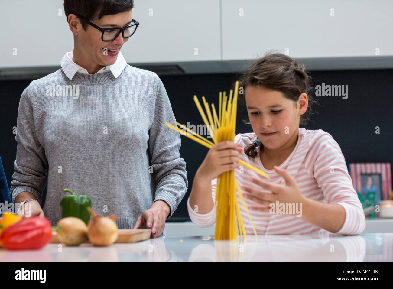 Hija ayudando a mamá cocinar espaguetis Foto de stock