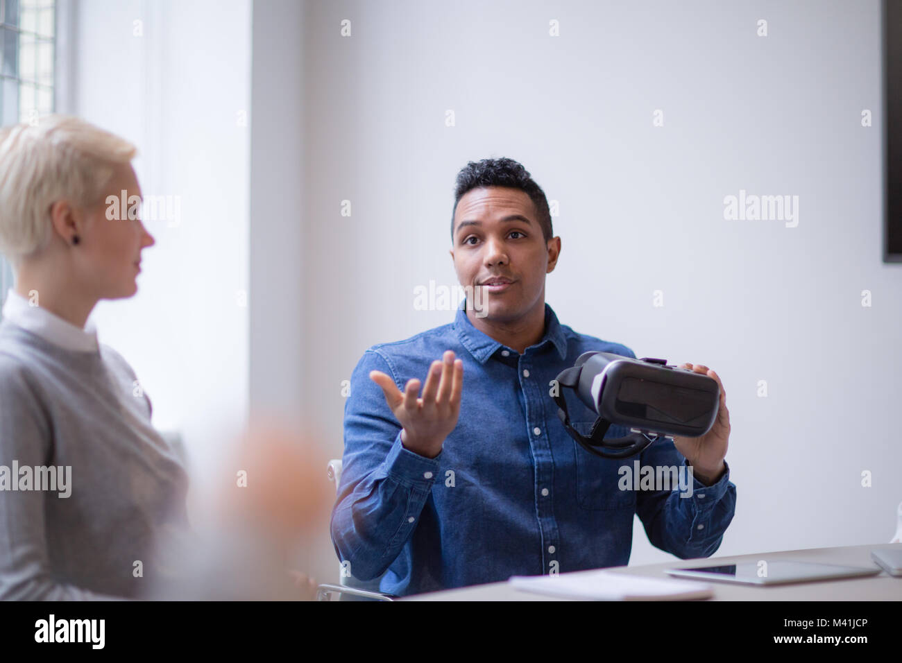 Diseñador presentando casco de realidad virtual en una reunión Foto de stock