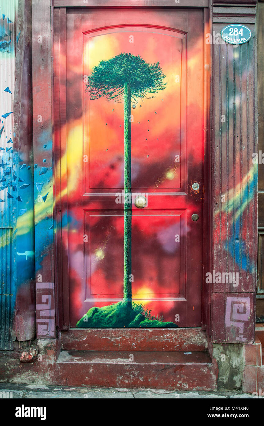 Una escena en la calle de la puerta de una casa de madera pintada con un colorido mural de un pehuén Foto de stock
